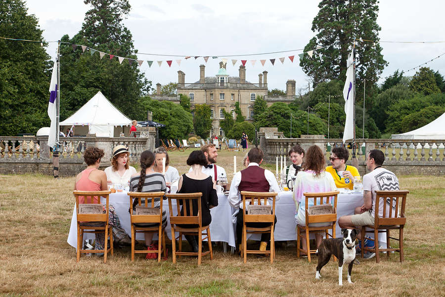 A photograph of people eating at a dining table on the lawn